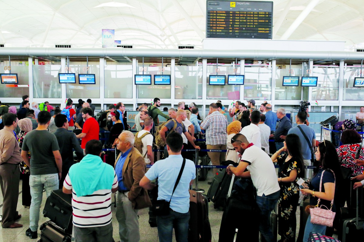 People stand in line in front of check-in desk to leave northern Iraq at Erbil International Airport in Erbil, Iraq, yesterday.