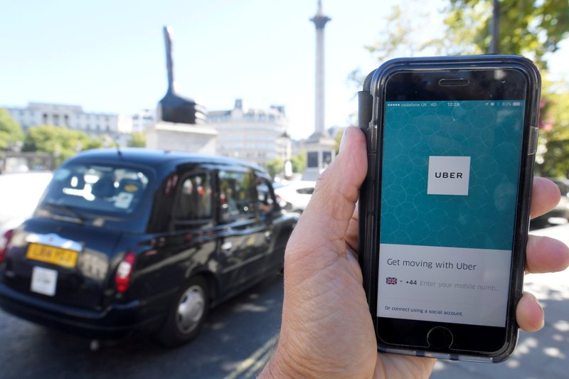 FILE PHOTO: A photo illustration a London taxi passing as the Uber app logo is displayed on a mobile telephone, as it is held up for a posed photograph in central London September 22, 2017. REUTERS/Toby Melville/File Photo
