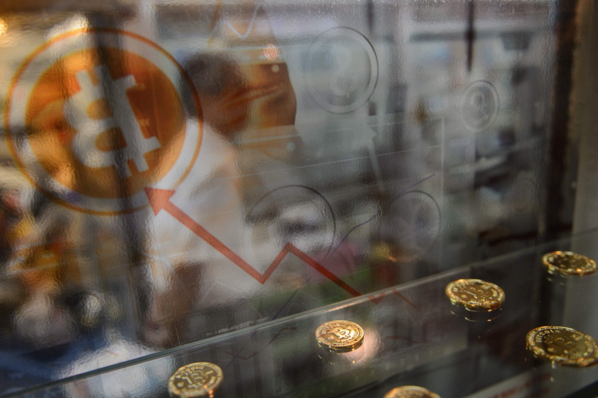 A man walking past a display cabinet containing models of Bitcoins in Hong Kong on August 3, 2016. (AFP / Anthony Wallace) 