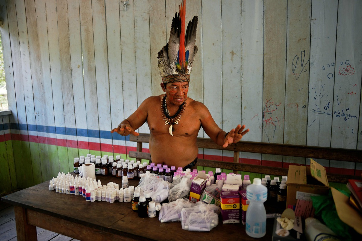 Chief Marcelino Apurina, of the Aldeia Novo Paraiso in the Western Amazon region of Brazil near Labrea stands by a table of modern medicines delivered to the village on September 21, 2017.  AFP / Carl De Souza