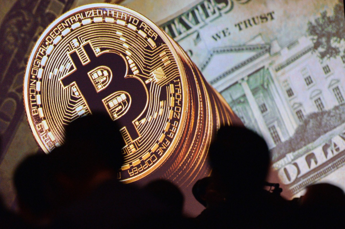 An image of Bitcoin and US currencies displayed on a screen as delegates listen to a panel of speakers during the Interpol World Congress in Singapore on July 04, 2017 (AFP / Roslan Rahma) 