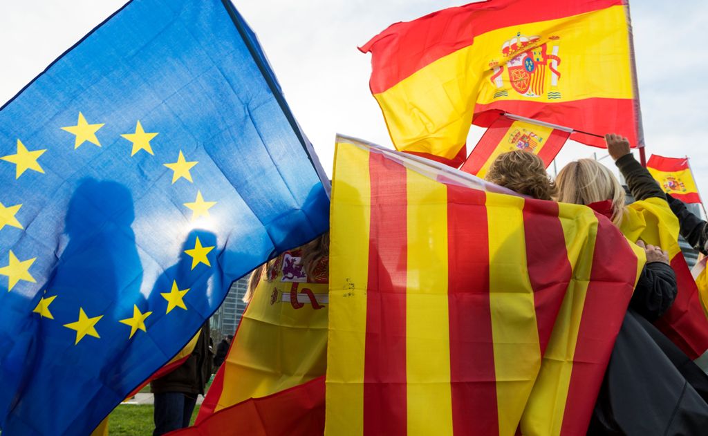 Women hold Spanish, Catalan and European flags during a demonstration against Catalonia's independence in front of the European Parliament building in Strasbourg, eastern France, on October 24, 2017. AFP / PATRICK HERTZOG
