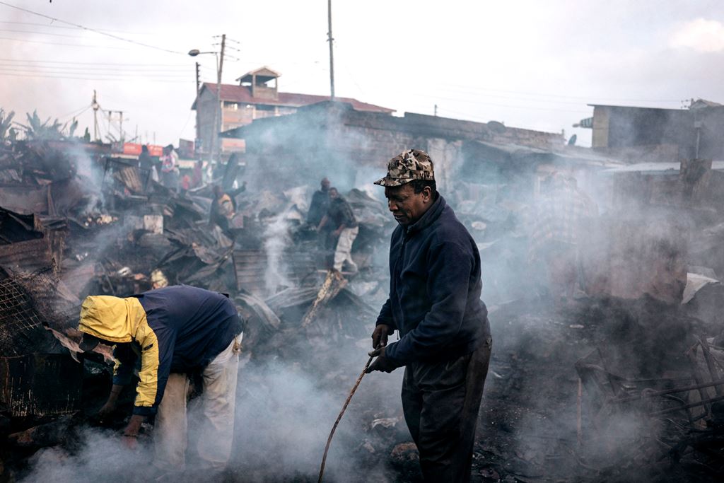 Residents walk amid the remains of market stalls that were burnt to the ground during protests relating to the presidential election in the Kamangware district of Nairobi on October 28, 2017. AFP / Marco LONGARI