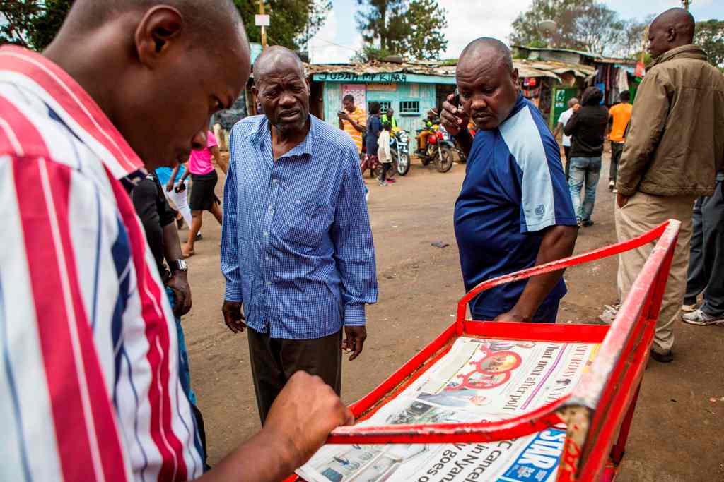 Residents of Nairobi's Kibera slum, a stronghold of Kenyan opposition leader, follow up presidential election coverage in the newspaper while waiting official results.  AFP / Patrick Meinhardt
