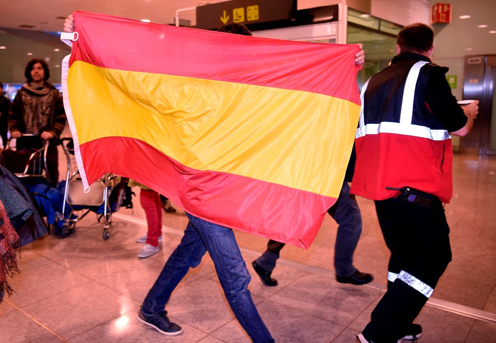 A person holds a Spanish flag at El Prat airport in Barcelona where some members of the dismissed government of Catalonia arrived from Brussel on October 31, 2017.