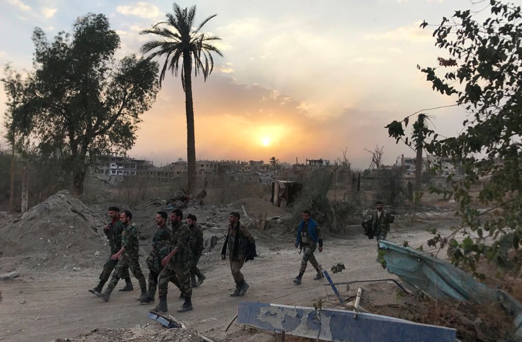 Syrian government forces walk through a road in a northeastern district of Deir Ezzor on November 5, 2017, after retaking the city from Islamic State (IS) group jihadists.  AFP / STRINGER
