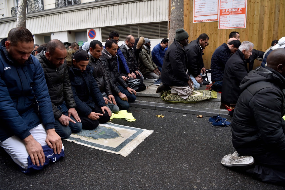 People pray in a street on November, 10, 2017, in Clichy, near Paris, while the city mayor Remi Muzeau, demonstrate with others political leaders against muslims streets prayers. AFP / Alain Jocard