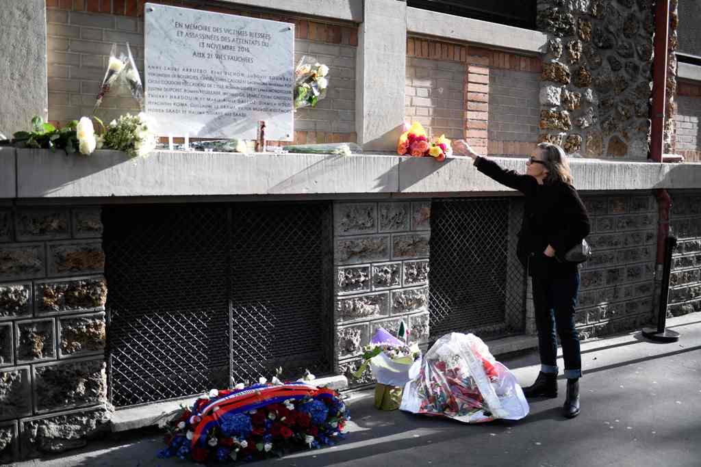 A woman lays a bunch of flowers near a plaque commemorating the victims of a shooting at La Belle Equipe cafe - restaurant during ceremonies across Paris marking the second anniversary of the terror attacks of November 2015 in which 130 people were killed