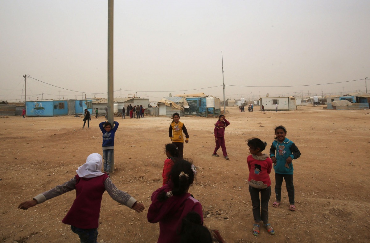 Syrian refugee children play during a sand storm at the Zaatari refugee camp on November 13, 2017. Some 80,000 Syrian refugees living in the Zaatari camp will have access to 14 hours of electricity per day instead of eight hours, thanks to the opening of 