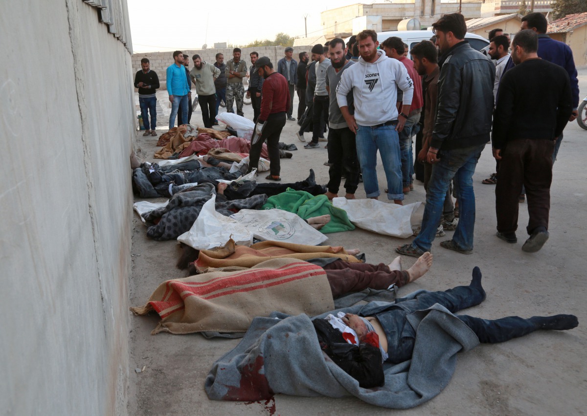 People gather next to bodies following a reported airstrike on the rebel-held town of Atareb in Syria's northern Aleppo province on November 13, 2017. AFP / Zein Al Rifai