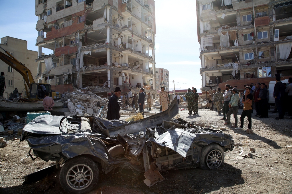  People inspect the debris of buildings and a destroyed vehicle at Sarpol-e Zahab province of Kermanshah, Iran on November 13, 2017 following a 7.3 magnitude earthquake that hit the Iraq and Iran. Anadolu Agency/ Fatemeh Bahrami