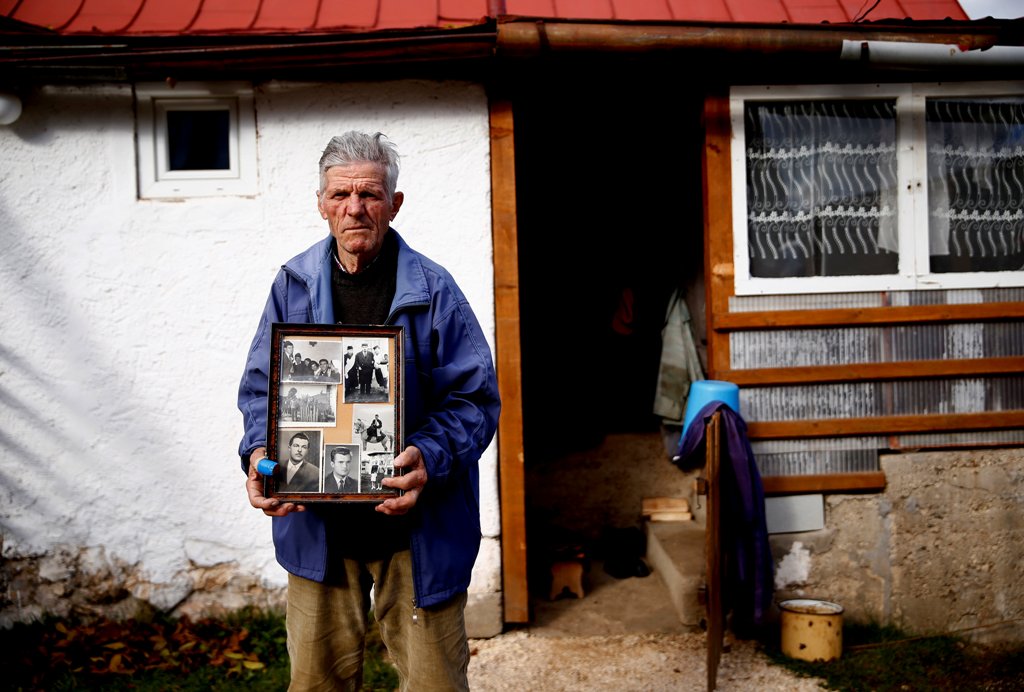 A file photo of Mile Mladic, a cousin of the former Bosnian Serb military commander Ratko Mladic, poses for a photograph holding old family photos of Ratko Mladic and his family in front of his home, in the village where Ratko Mladic was born, Bozanovici,