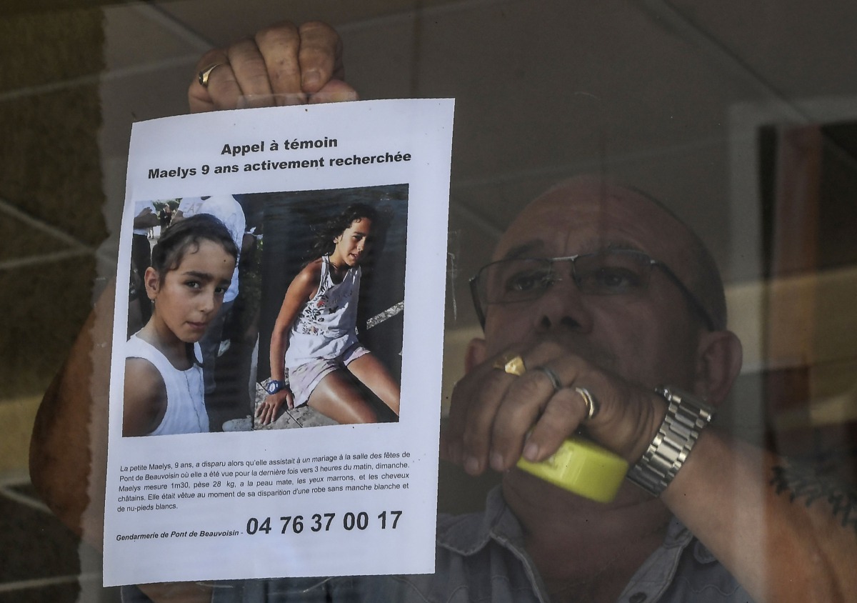 This file photo taken on August 28, 2017 shows the owner of a bar attaching an appeal for witnesses poster issued by the Gendarmerie of Pont-de-Beauvoisin for Maelys, a 9-year-old girl, who disappeared during a wedding party on August 26 overnight. AFP / 