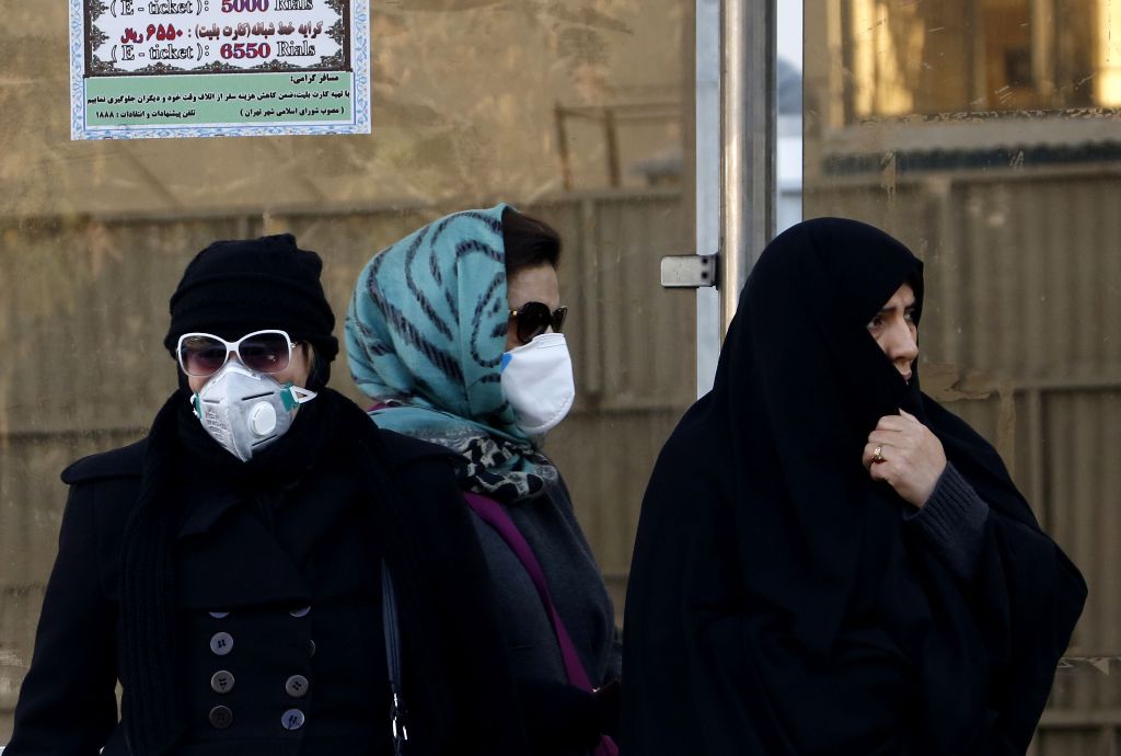  Iranian women wearing face masks wait at a bus stop as winter's heavy pollution has hit new highs in the capital Tehran, on December 17, 2017. / AFP / ATTA KENARE