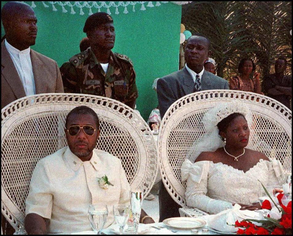 A file photo of then Liberian warlord and presidential aspirant Charles Taylor and Deputy Governor of the National Bank of Liberia Jewel Howard (both seated), who married January 28, in the central Liberian town of Gbarnga July 26, 1996. / AFP / FRANCOIS 