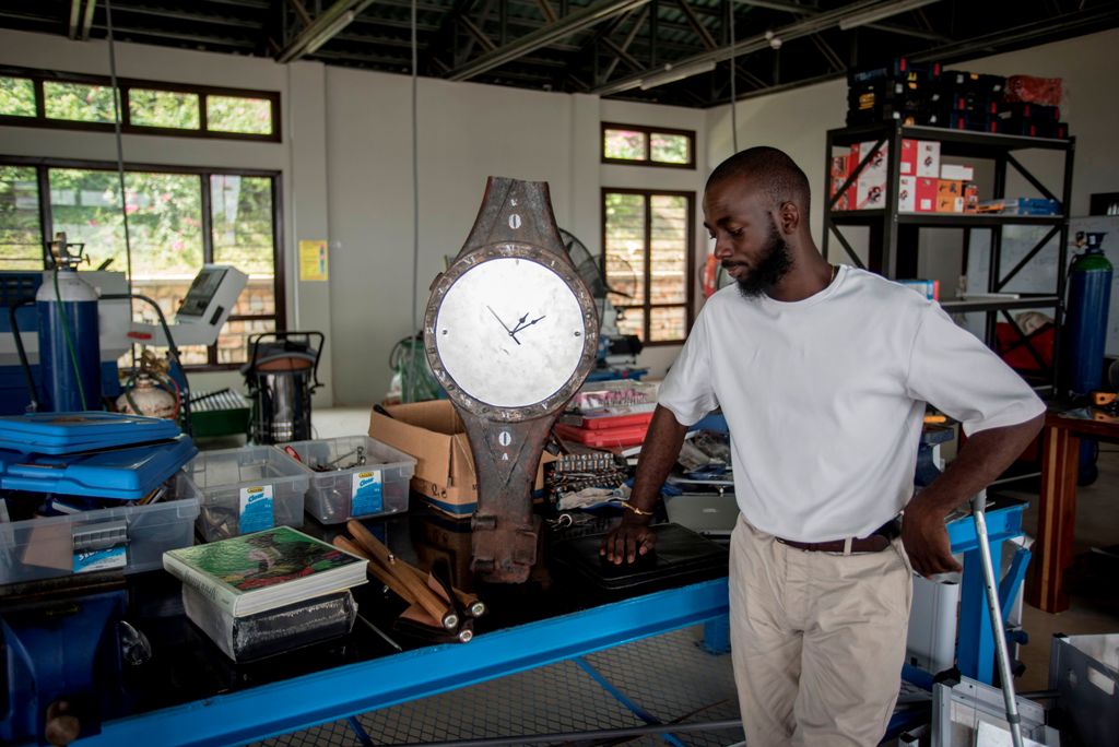 File photo of Ghanaian artist Joseph Awuah-Darko working on a clock, the pieces of which were found at Agbogloshie dumpsite, at his workshop at Ashesi University College where he studies, outside Accra on November 29, 2017. / AFP / CRISTINA ALDEHUELA