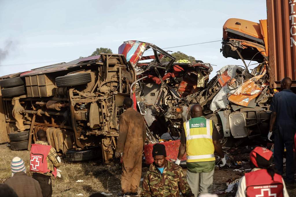 Emergency workers stand near the wreckage of a bus and a lorry that crashed in a head-on collision, killing thirty people, at the accident scene near Nakuru, Kenya, on December 31, 2017. / AFP.