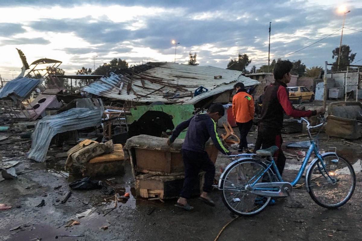 Two Iraqi children walking with a bicycle at the scene of a blast by a massive car bomb which killed dozens in a used car market in southern Baghdad on February 16, 2017 (AFP) 