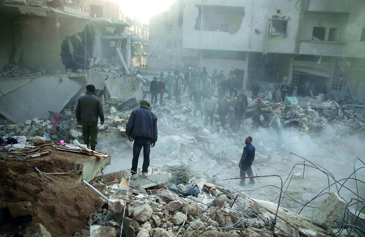 People stand on rubble of damaged buildings, after an airstrike in the besieged town of Hamoria, Eastern Ghouta, in Damascus, Syria Janauary 9, 2018. Reuters/Bassam Khabieh