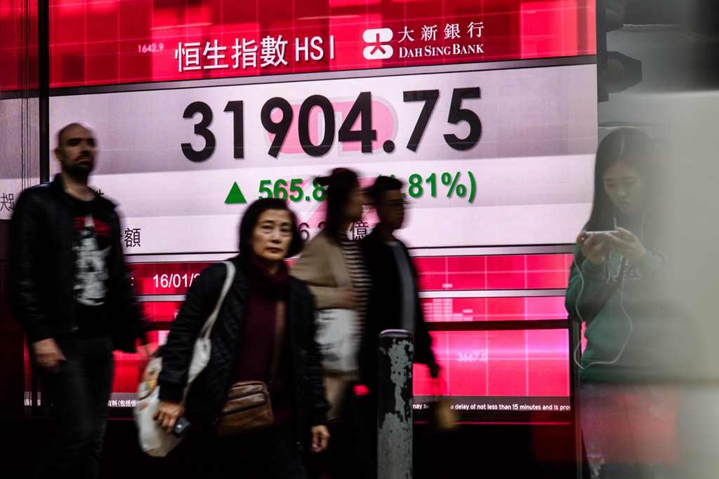 Pedestrians walk past stocks display board after the Hang Seng Index leapt 1.81 percent, or 565.88 points, to close at 31,904.75 in Hong Kong on January 16, 2018. AFP / Anthony WALLACE
