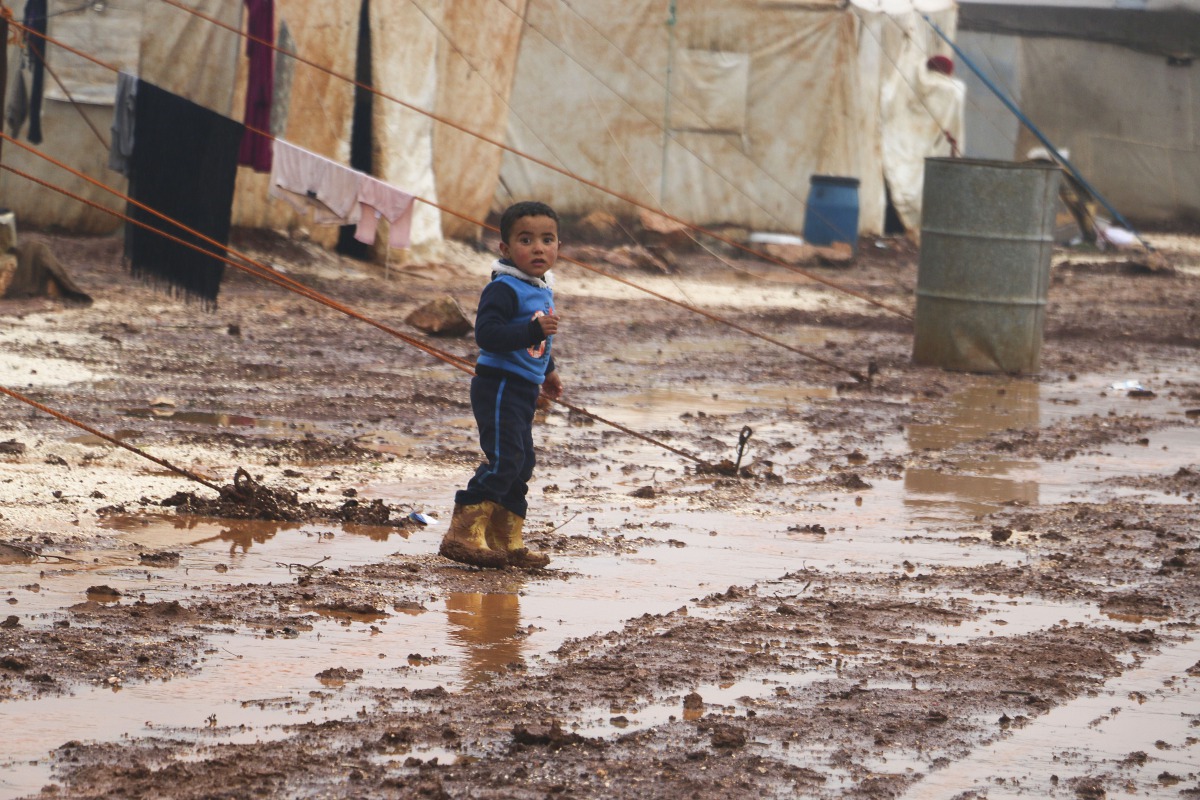 A Syrian kid walks around through mud at a refugee camp where many Syrians lived in, following the heavy rains in Idlib, Syria on January 18, 2018. (Alaa Fatravi - Anadolu Agency)