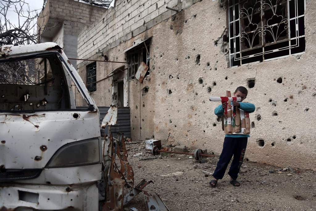 A Syrian child plays with a cardboard gun in the rebel-held town of Harasta, in the Eastern Ghouta region on the outskirts of Damascus on January 25, 2018. / AFP / ABDULMONAM EASSA