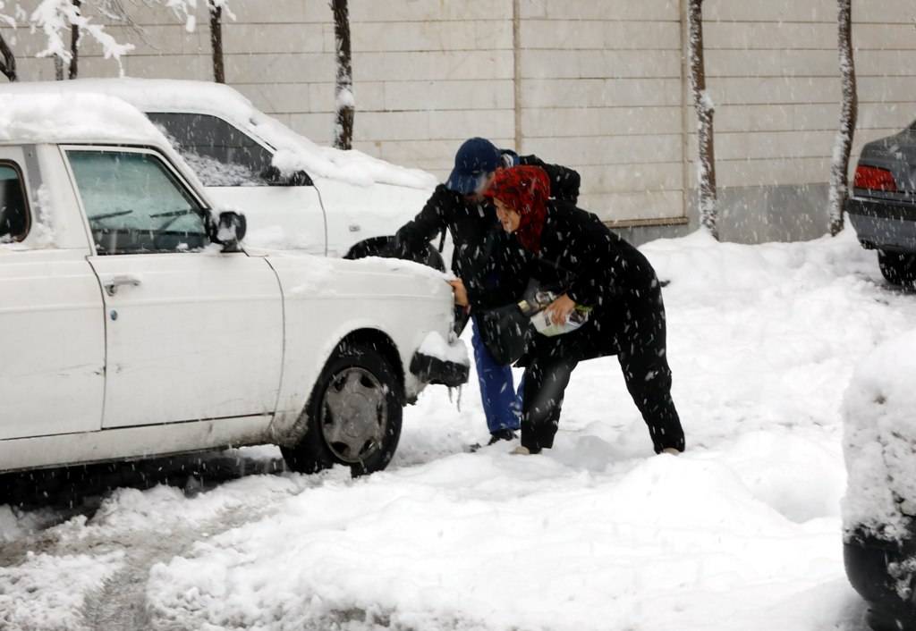 An Iranian couple tries to help a car which is stuck in snow in a street during a heavy snowfall in Tehran, Iran, 28 January 2018. EPA/ABEDIN TAHERKENAREH