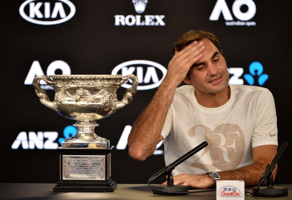 Switzerland's Roger Federer sits next to the Norman Brookes Challenge Cup during a press conferecen after beating Croatia's Marin Cilic in their men's singles final match on day 14 of the Australian Open tennis tournament in Melbourne on early January 29,