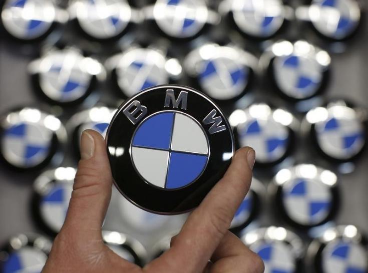 An employee holds a BMW logo on the production line of the BMW C evolution electric maxi-scooter at the BMW Berlin motorcycle plant, February 23, 2015. (Reuters / Fabrizio Bensch) 