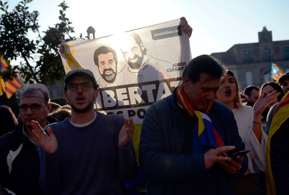 A protester holds a banner depicting images of Catalan separatist leaders Jordi Cuixart and Jordi Sanchez during a demonstration outside the Catalan Parliament on January 30, 2018 in Barcelona. AFP / Josep LAGO

