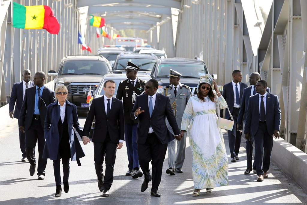French President Emmanuel Macron (2ndL) and Senegalese President Macky Sall (2ndR), with their wives Brigitte Macron (L) and Marieme Faye Sall (R), cross the Faidherbe bridge in Saint-Louis, Senegal, February 3, 2018. REUTERS/Ludovic Marin/Pool
