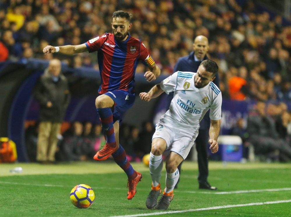 Real Madrid’s Dani Carvajal in action with Levante's Jose Morales as Real Madrid coach Zinedine Zidane looks on REUTERS/Heino Kalis