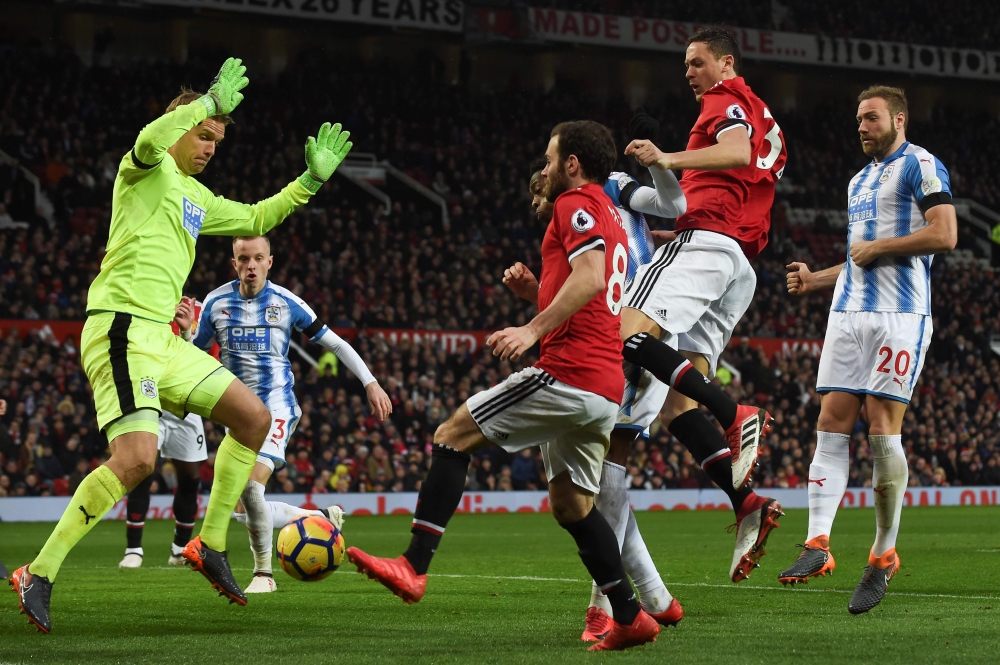 Huddersfield Town's Danish goalkeeper Jonas Lossl (L), Manchester United's Spanish midfielder Juan Mata (C) and Manchester United's Serbian midfielder Nemanja Matic (2R) scramble for the ball in the Huddersfield goal mouth during the English Premier Leagu