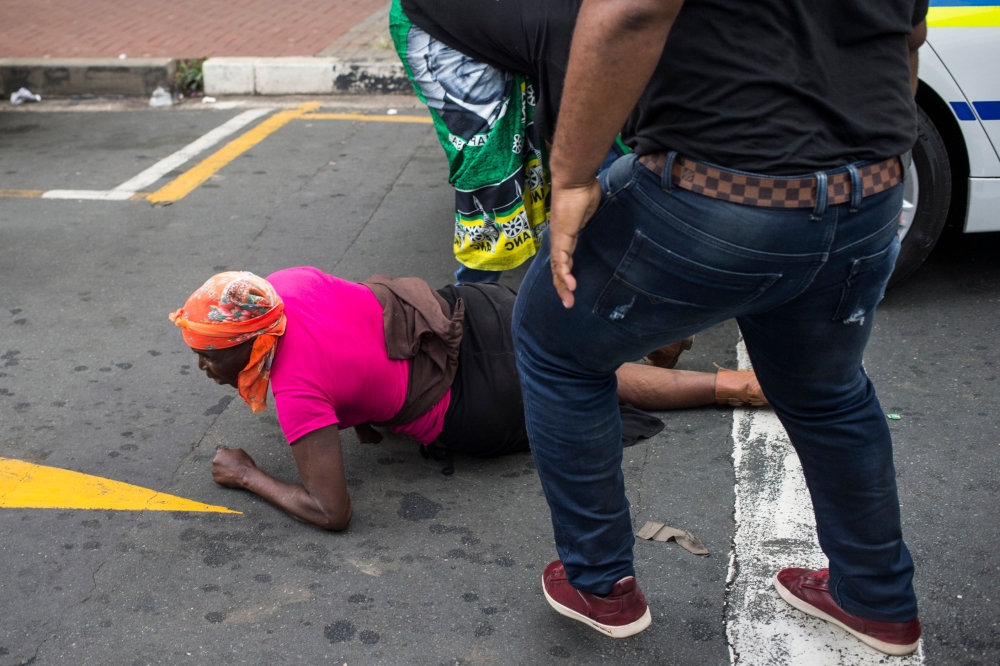 ANC (African National Congress) members attack a woman they suspect of being a member of the BLF (Black Land First) movement, outside the ANC headquarters in Johannesburg on February 5, 2018. AFP / Wikus De Wet