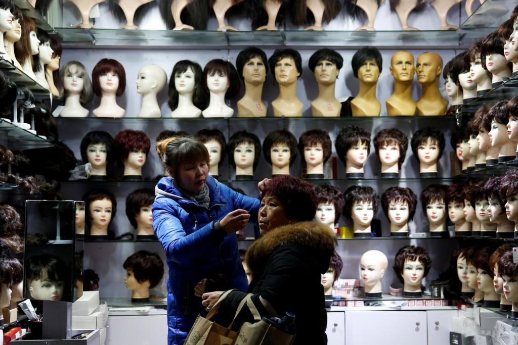 File photo of a vendor, helps put on a wig on a customer at a wig shop near the central train station in Shanghai, China January 18, 2017. REUTERS/Aly Song/File Photo