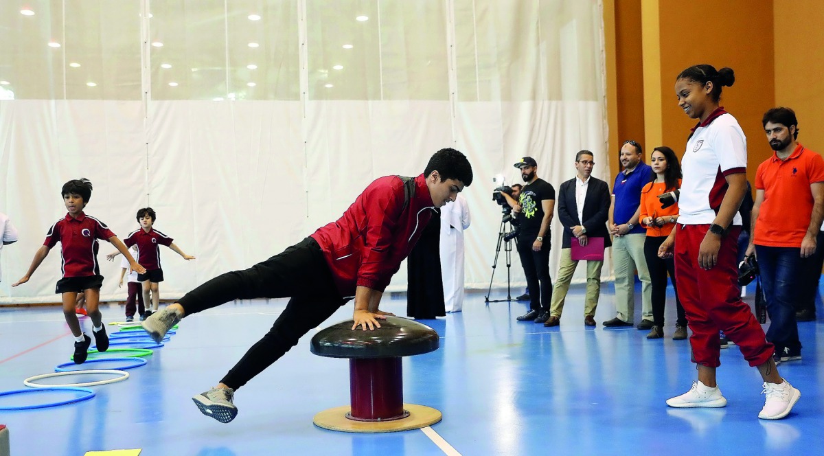 A Qatari gymnast demonstrates his skills to schoolchildren during last year’s National Sport Day in this file photo. INSET: Young boxers show off their skills during the 2017 National Sport Day. 