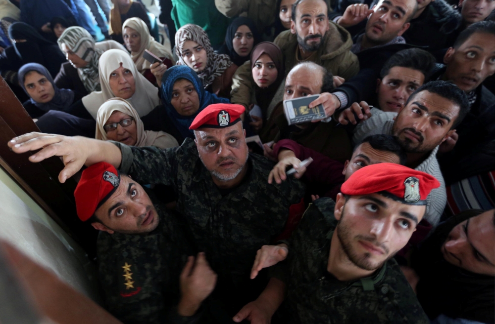 Members of Palestinian Hamas security forces stand guard as people ask for travel permits to cross into Egypt through the Rafah border crossing after it was opened by Egyptian authorities for humanitarian cases, in the southern Gaza Strip February 7, 2018