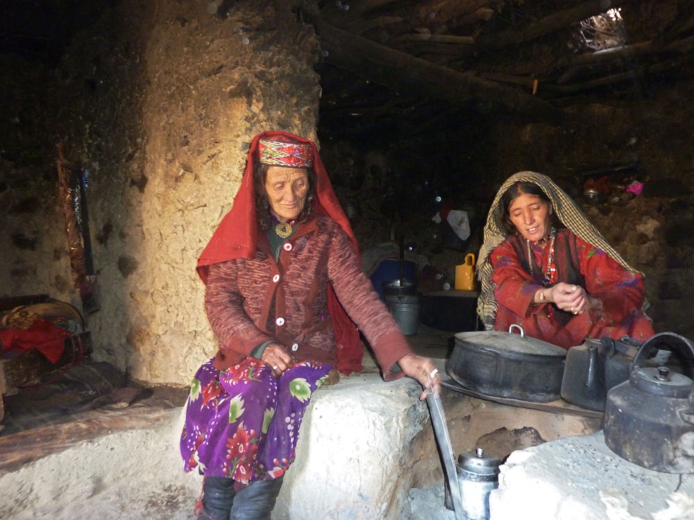 This photograph taken on October 8, 2017 shows Afghan Wakhi nomadic woman Sultan Begium (L) and her daughter-in-law preparing food inside their mud home in the Wakhan Corridor in Afghanistan. AFP / Gohar Abbas
