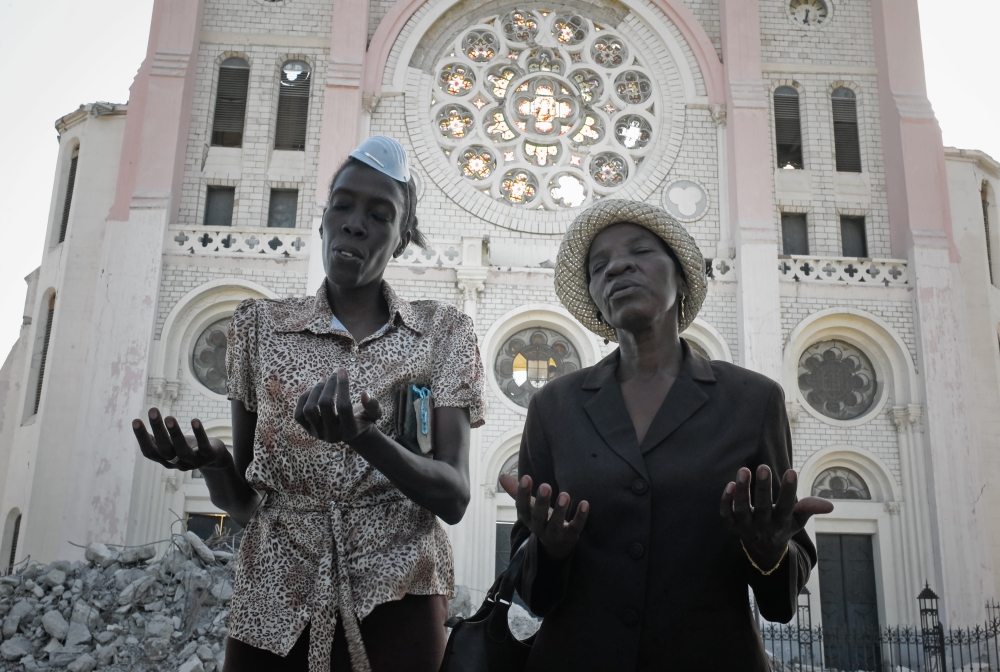 In this file photo taken on January 24, 2010 Haitians pray during mass outside the ruined cathedral in Port-au-Prince following a devastating earthquake.  AFP / Jean-Philippe Ksiazek