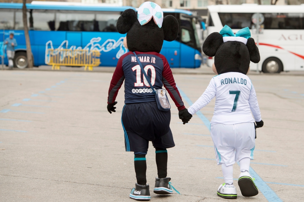 Supporters dressed as Paris Saint-Germain's Brazilian forward Neymar Jr and Real Madrid's Portuguese forward Cristiano Ronaldo walk outside the Santiago Bernabeu stadium in Madrid on February 14, 2018 hours before the Champions' League football match Real