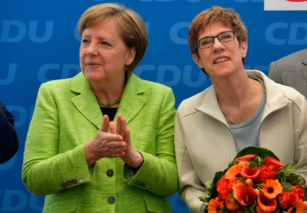 (FILES) This file photo taken on March 27, 2017 shows German Chancellor Angela Merkel (L) applauding Annegret Kramp-Karrenbauer after she won regional elections in the southwestern federal state of Saarland, during a meeting with the leadership of their c