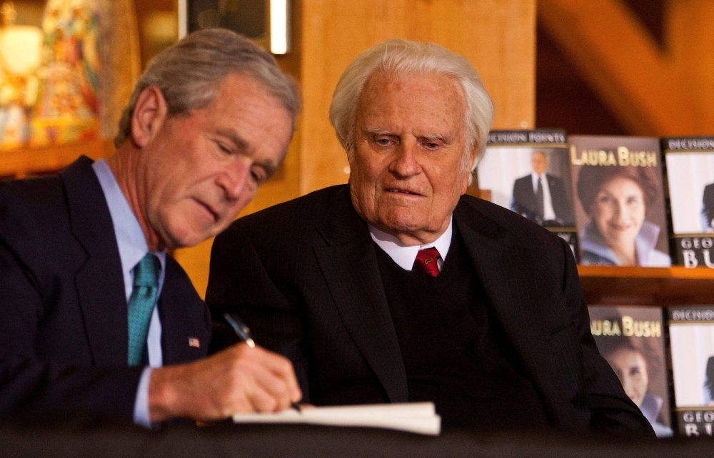 Former US President George W. Bush (L) signs a copy of his new book 