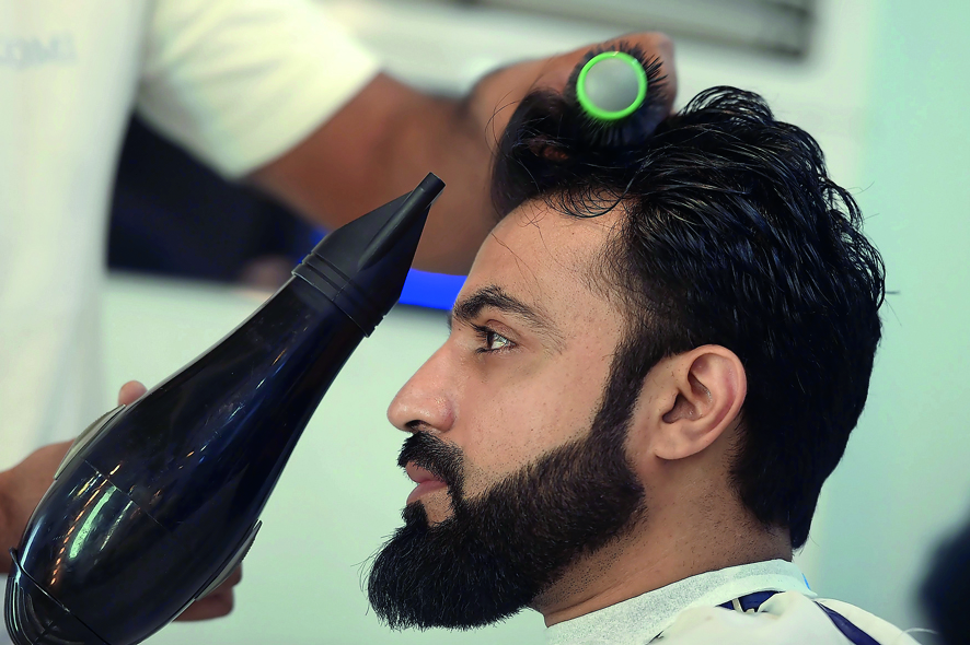 This photograph taken on October 12, 2017 shows a male hairdresser blow-drying a customer's hair at a men's salon in Islamabad. 