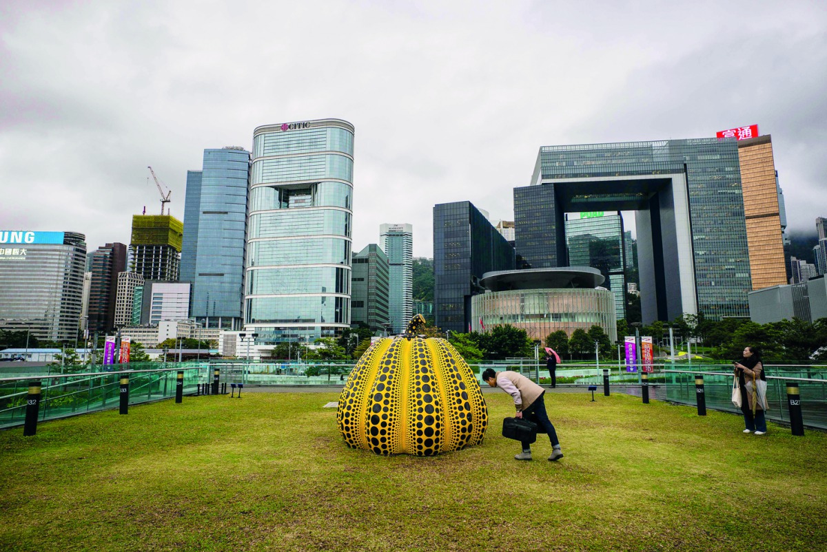 Visitors look at Japanese artist Yahoo Kusama's 'pumpkin: big, 2008' at the Harbour Arts Sculpture Park in Hong Kong on February 22, 2018.  AFP / Anthony Wallace