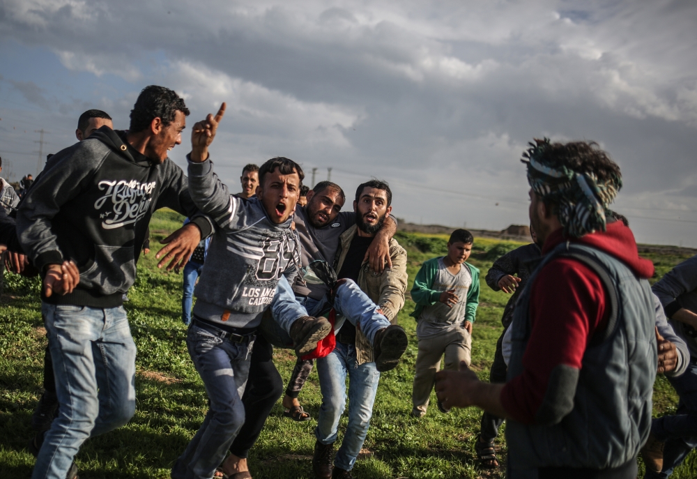 Palestinians carry a wounded man during a protest against US President Donald Trump’s announcement to recognize Jerusalem as the capital of Israel, in Shuja'iyya neighborhood of Gaza City, Gaza on February 23, 2018. (Ali Jadallah /Anadolu Agency)