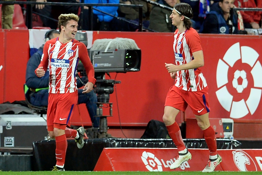Atletico Madrid's French forward Antoine Griezmann (L) celebrates after scoring a goal during the Spanish league football match between Sevilla FC and Club Atletico de Madrid at the Ramon Sanchez Pizjuan stadium in Sevilla on February 25, 2018. / AFP / Cr