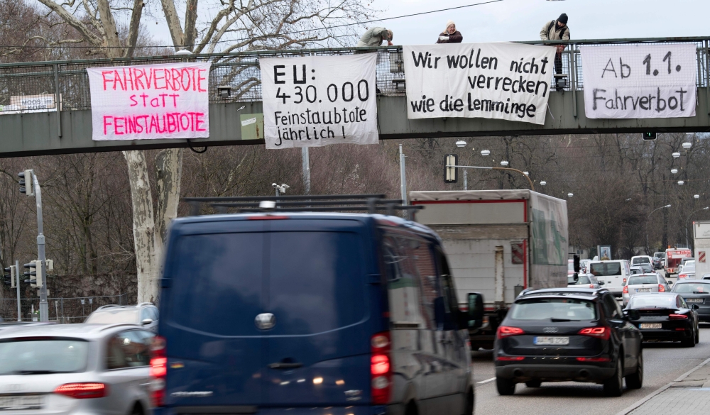 Protesters on a bridge hold banners to protest against particulate pollution as vehicles drive on a busy road on February 1, 2018 at a traffic junction of the Neckartor roadway, a Stuttgart neighbourhood which is a hotspot for air pollution. The banner (C
