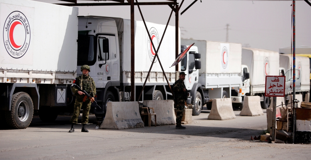 Russian soldiers are seen securing Syrian Arab Red Crescent trucks carrying aid at a checkpoint near Wafideen camp in Damascus, Syria March 5, 2018. REUTERS/Omar Sanadiki