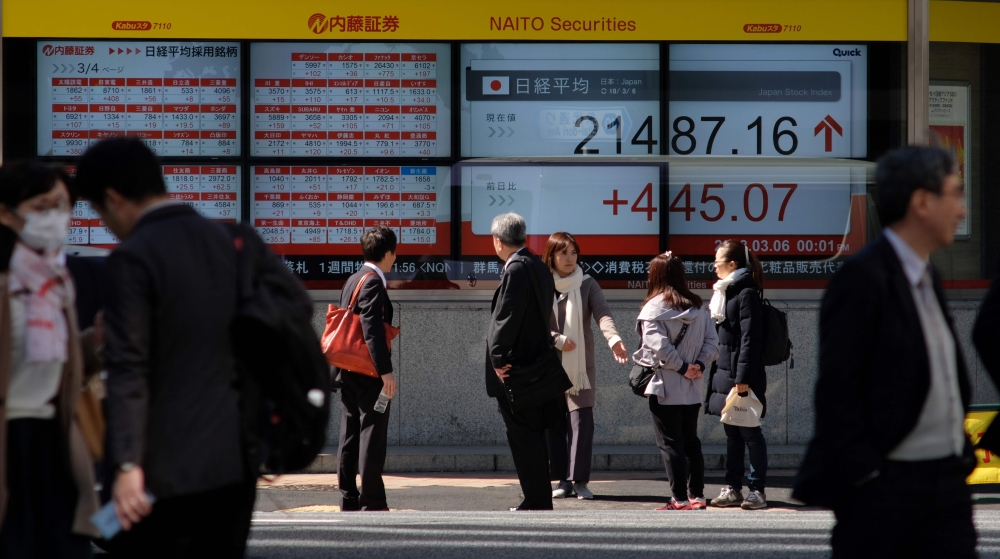 Pedestrians walk past at an electronic stock indicator showing share prices of the Tokyo Stock Exchange in Tokyo on March 6, 2018. AFP / Kazuhiro Nogi 