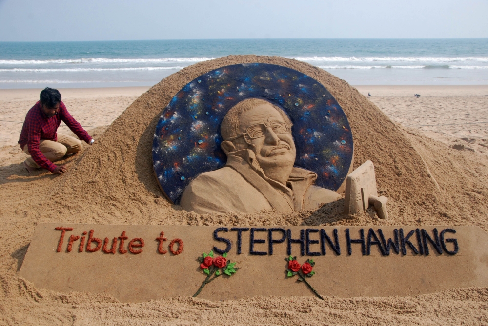 Sand artist Sudarsan Patnaik gives final touches to a sculpture in honour of British physicist and award-winning author Stephen Hawking at Puri beach, some 65 kms. from Bhubaneswar on March 14, 2018.  AFP / Asit Kumar